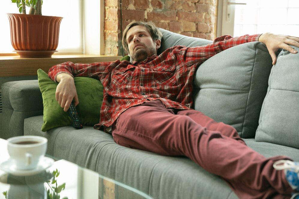 Alt text: Man recovers on a couch from a late night of partying.
