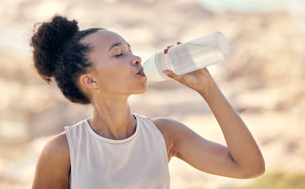 A woman drinks from bottled water after working out.