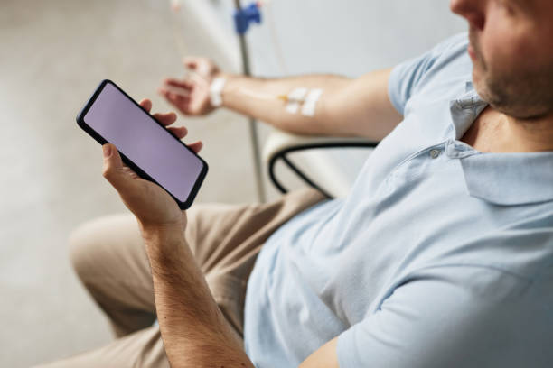 A man checks his phone during an IV treatment.