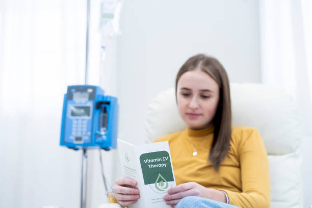 A woman reads a pamphlet about IV infusions while waiting for treatment.