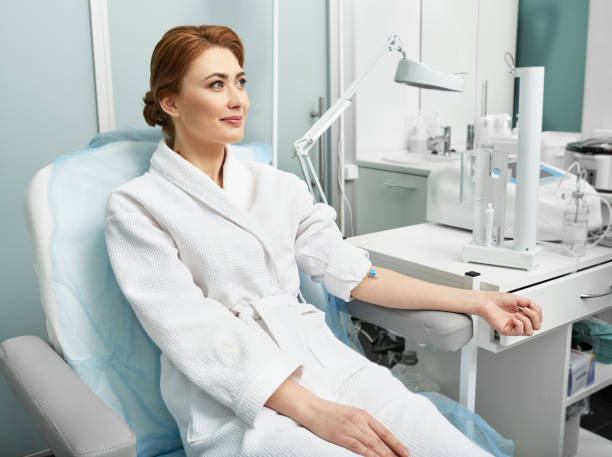 A woman sits in a doctor's chair, receiving advice on skin hydration.