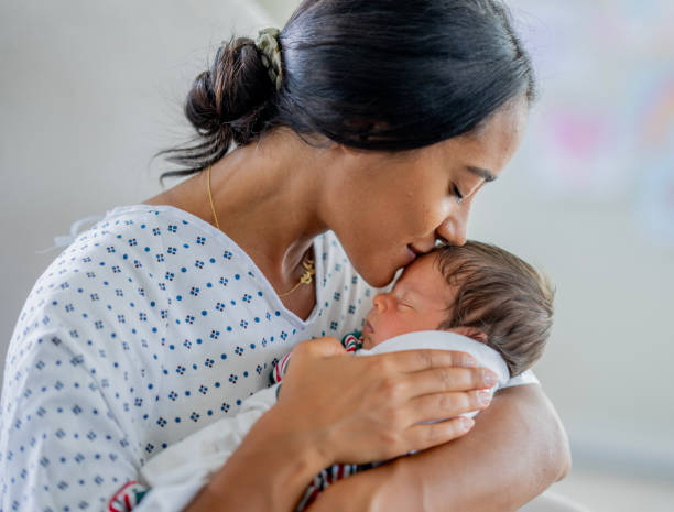 A new mom holds and kisses her newborn baby.